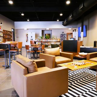 Elkhart County Visitor Center cozy interior with tan leather chairs, wooden tables, a striped rug, shelves, and decor on the walls.