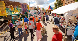 Nappanee Apple Festival street with vendors, attractions, and crowd enjoying sunny day.