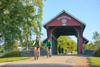 Two people biking on a trail on the grounds of Das Dutchman Essenhaus in Middlebury, IN.